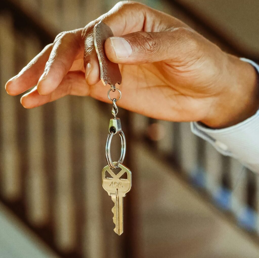 A close-up shot of a hand holding a house key, indicating new ownership or rental.